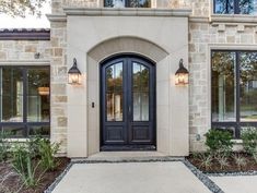 the front entrance to a home with two large doors and three lights on each side