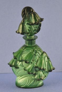 a green glass vase sitting on top of a table