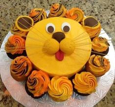 a lion cake with cupcakes in the shape of it's face on a plate