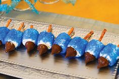 blue and white desserts are lined up on a silver platter with toothpicks