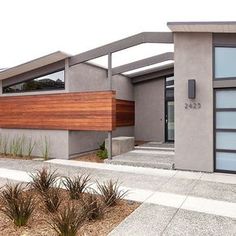 a modern house with wood and glass on the front door, side entrance and entry way