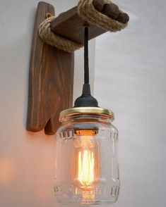 a mason jar hanging from the side of a wall next to a light fixture with rope on it