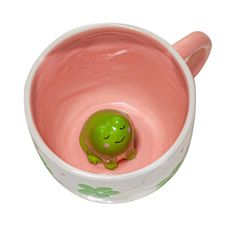 a ceramic bowl with a small green turtle in it's mouth and the lid is pink