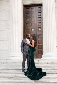 a man and woman standing on steps in front of a building with columns holding each other