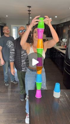 a group of people standing in a kitchen next to a table with cups on it