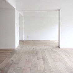 an empty room with white walls and wood floors is pictured in this image from the side