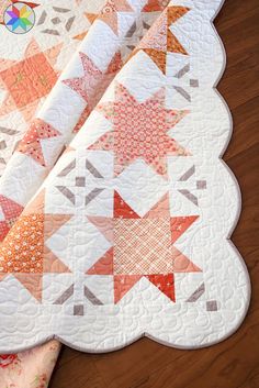 two quilts are laying on the floor next to each other, one has an orange and white star