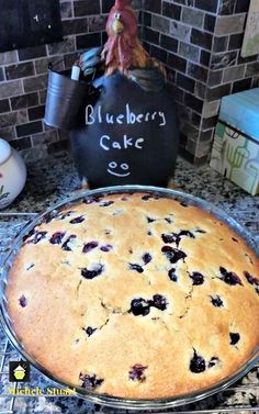 a blueberry cake sitting on top of a counter next to a blackboard sign