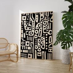 a large black and white abstract painting on a wall next to a wicker chair