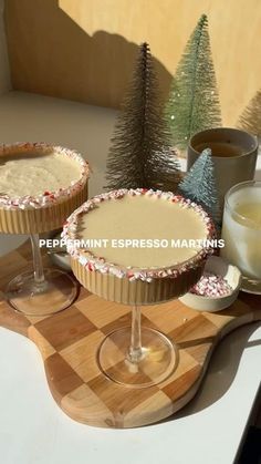 two desserts sitting on top of a wooden cutting board next to cups and saucers