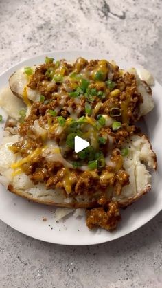 a white plate topped with cheesy potatoes covered in ground beef and green onions