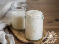 two jars filled with white liquid sitting on top of a wooden tray