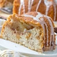 a close up of a piece of cake on a plate with icing and apples