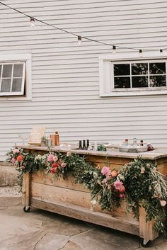 an outdoor bar is decorated with flowers and greenery for a wedding reception at the barn