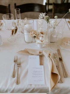 the table is set with silverware and flowers