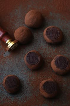 chocolate truffles with initials on them are next to a waxed wooden pen