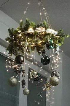 a chandelier with christmas decorations hanging from it's sides and lights on