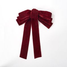 a red velvet bow tied on top of a white surface with one end partially closed