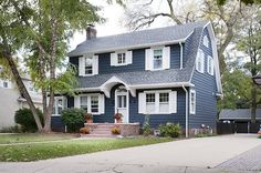 a blue house with white shutters on the front and side windows is shown in this image