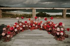 flowers arranged in the shape of a heart on a walkway near the beach and ocean