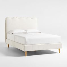 a bed with white linen and wooden legs