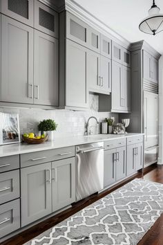 a large kitchen with gray cabinets and white counter tops, an area rug and light wood flooring