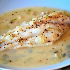 a close up of a plate of food with broccoli and fish in gravy