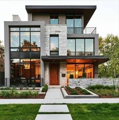 a large modern house with lots of windows and grass in front of the entrance to it