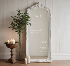 a white framed mirror sitting on top of a wooden floor next to a potted plant