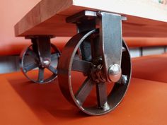 a close up of a metal wheel on an orange couch with wheels attached to it