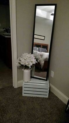 a mirror sitting on top of a white table next to a vase filled with flowers