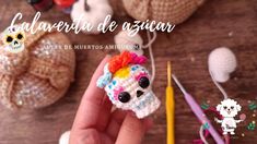 a hand holding a small crocheted skull with a colorful hairdow on it's head