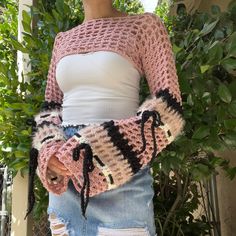 a woman is wearing a pink and black crochet sweater with laces on the sleeves