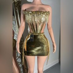 a mannequin wearing a gold dress with fringes on it's shoulders