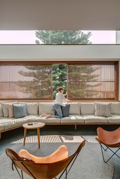 a man sitting on top of a couch in a living room next to a window