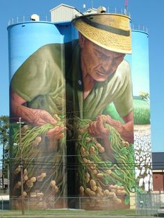 a large painting on the side of a building with a man working in his hands