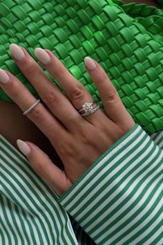 a woman's hand with white and green manies holding onto a green purse