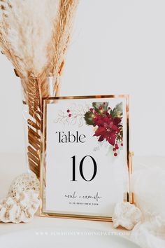 the table numbers are displayed in front of a vase filled with dried flowers and feathers