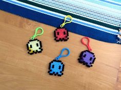 four pixel keychains sitting on top of a wooden table next to a blue and white towel