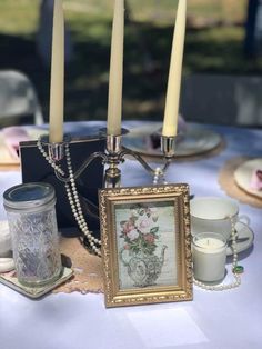 a table topped with candles and pictures on top of a white table cloth covered table