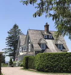 a large house sitting next to a lush green forest filled with lots of greenery