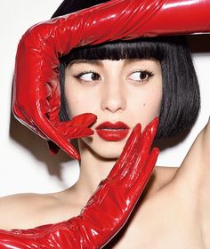 a woman wearing red gloves and holding her hands up to her face