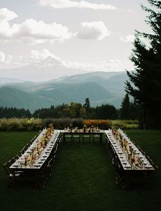 a long table set up in the middle of a field with mountains in the background