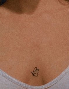 a woman's chest with a small butterfly tattoo on the left side of her breast