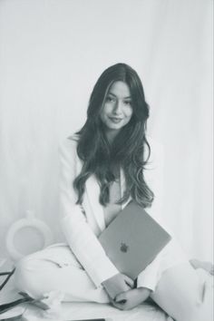 a black and white photo of a woman sitting on the floor holding an apple laptop