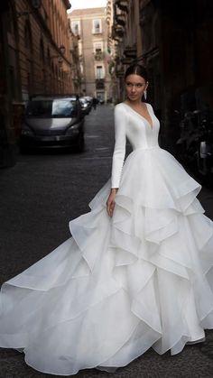 a woman in a white wedding dress standing on the street