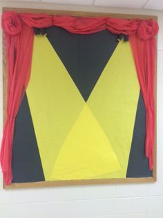 a yellow and black piece of art hanging on the wall next to a red curtain