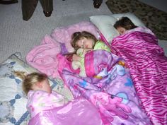 three children sleeping in blankets on the floor