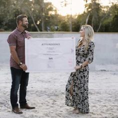 a man standing next to a woman holding a large check