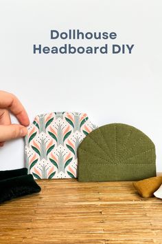 a hand is holding a piece of paper next to other items on a table with the words dollhouse headboard diy written above it